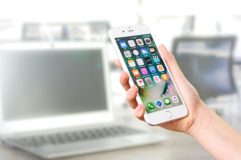 A person's hand holding a silver iPhone 7